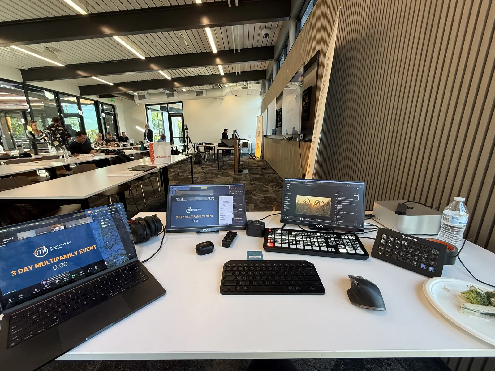 The same desk set up at a live event, with a full room of attendees behind it